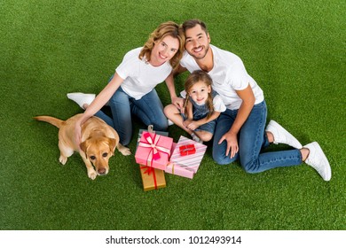 High Angle View Of Family With Wrapped Gifts Sitting On Green Grass