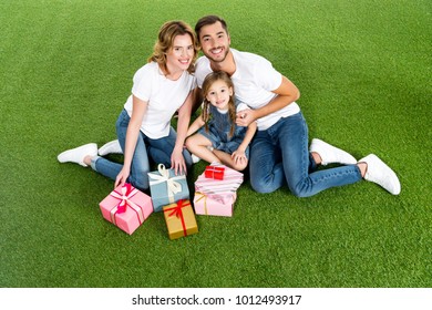 High Angle View Of Family With Wrapped Gifts Sitting On Green Grass