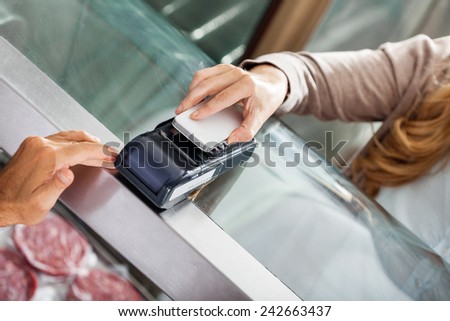 High angle view of female customer making payment through smartphone in butchery