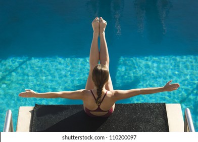 High Angle View Of A Female Diver On Diving Board With Arms Out