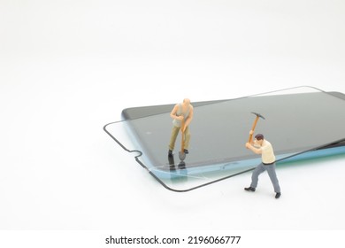 High Angle View Of Figurines On Broken Mobile Phone