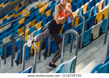 high angle view of fit young woman stretching on tribunes at sports stadium