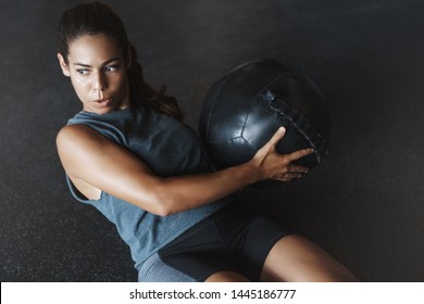 High angle view focused motivated strong woman workout sitting gym floor, breathing determined, training crunch abs holding medicine ball. Athletic sportswoman perform crossfit fitness exercise - Powered by Shutterstock