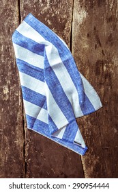 High Angle View Of Folded And Crumpled Blue And White Striped Linen Napkin On Rustic Wooden Table Surface