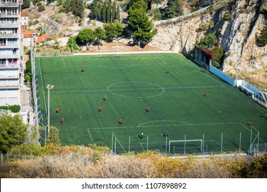 High Angle View Of A Football Stadium With Players On Action Near Notre Dame De La Garde Church