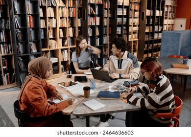 High angle view of four ethnically diverse male and female college students sitting in modern university library doing homework - Powered by Shutterstock