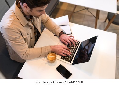 High angle view of freelancer typing on laptop keyboard in cafe