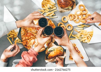 High Angle View Of Friends Eating Burger And French Fries At Table In Cafe.