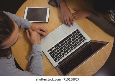 High angle view of friends using laptop at wooden table in cafe