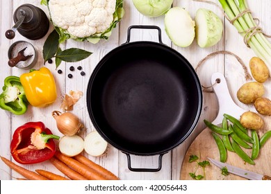 High Angle View of Frying Pan Wok Surrounded by Fresh Raw Vegetables and Spices Arranged Randomly on Painted Wooden Table Surface - Powered by Shutterstock