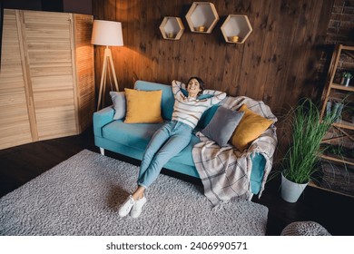 High angle view full size photo of nice girl sit couch arms behind head closed eyes have good mood loft flat inside
