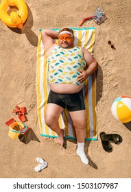 High angle view of funny overweight tourist resting on the beach