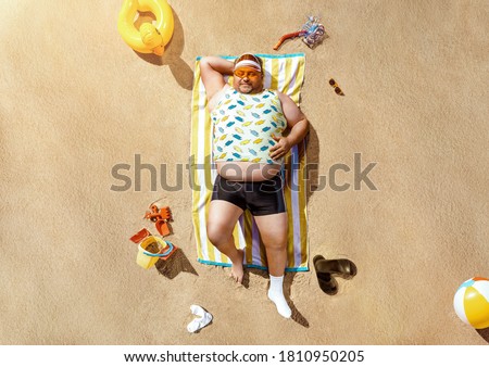 High angle view of funny overweight tourist resting on the beach