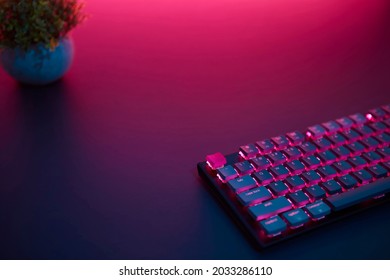 High Angle View Of Gaming Computer Keyboard Laying On Desk. Purple Light From Top. Professional Computer Game Playing, Esport Business And Online World Concept.