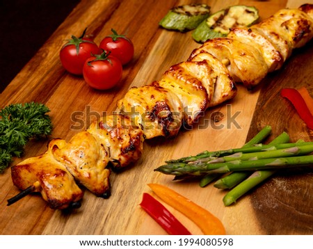 High angle view of grilled chicken kebab on a simple plate. Called Chelo Joojeh in Persian cuisine, as it is served with rice and grilled tomato.Fusion food barbecue concept.