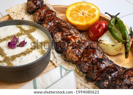 High angle view of grilled chicken kebab on a simple plate. Called Chelo Joojeh in Persian cuisine, as it is served with rice and grilled tomato.Fusion food barbecue concept.