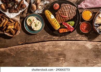 High Angle View of Grilled Meal of Steak, Chicken and Vegetables Spread Out on Rustic Wooden Table at Barbeque Party