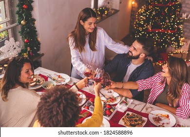 High Angle View Of Group Of Friends Making A Toast During Christmas Dinner, Raising Glasses Of Wine And Celebrating 