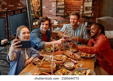 High Angle View At Group Of Friends Taking Selfie Photo At Table During Dinner Party And Clinking Glasses