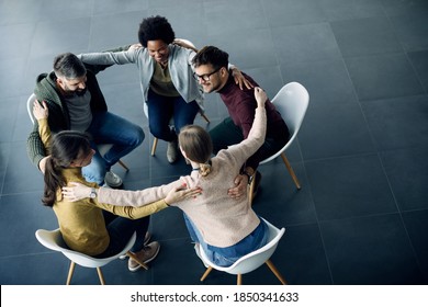 High angle view of group of supportive people sitting in a circle and embracing each other during group therapy. Copy space. 