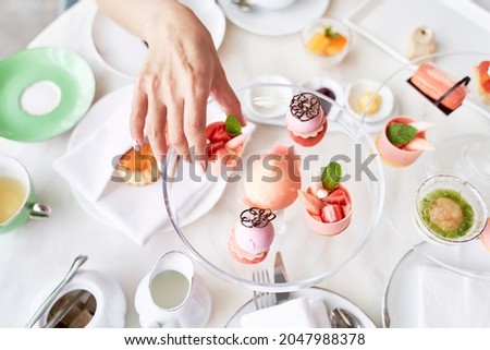 high angle view of hand of asian woman picking a dessert from glass plate on table