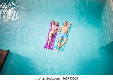 High angle view of happy couple relaxing on inflatable raft at swimming pool