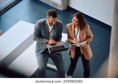 Vista de alto ângulo de colegas de trabalho felizes usando o notebook enquanto trabalham no escritório. Copiar espaço.