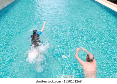 high angle view happy elderly caucasian husband and elderly asian wife swimming in pool during retirement holiday with relaxation on sunny day 