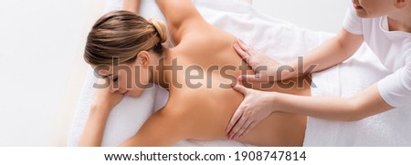 high angle view of happy masseur massaging back of young client on massage table, banner