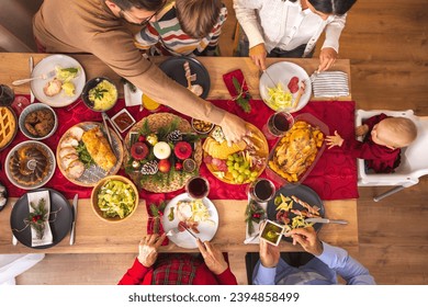 High angle view of happy multi-generation family gathered around the table, having Christmas dinner all together at home, speaking to each other and laughing - Powered by Shutterstock