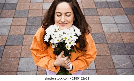 High Angle View Of Happy Woman With Closed Eyed Smelling White Flowers Outside