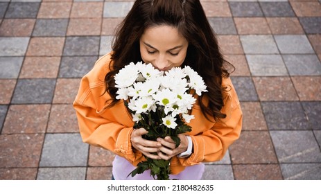 High Angle View Of Happy Woman Smelling Bouquet Of White Flowers Outside