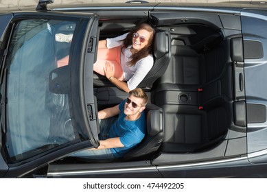 High Angle View Of Happy Young Couple Sitting In A Car
