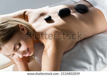 high angle view of happy young woman receiving hot stone massage