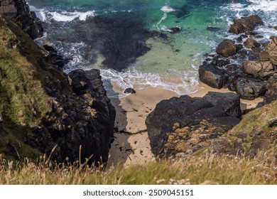 A high angle view of a hidden cove on the Cornish coast, on a sunny day - Powered by Shutterstock