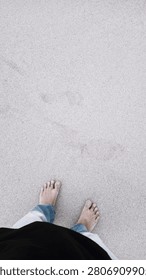 High angle view of human feet standing barefoot on a white sandy beach