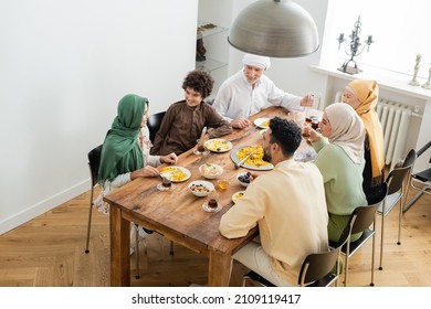 high angle view of interracial muslim family smiling during dinner at home