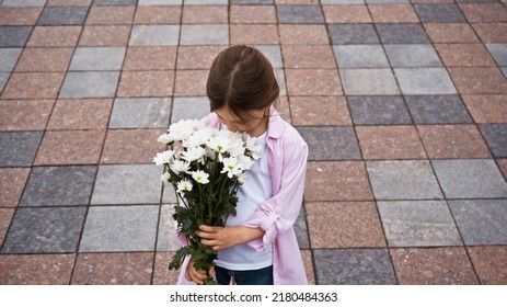 High Angle View Of Kid Smelling While Flowers Outside