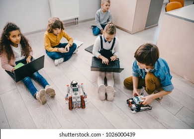 High Angle View Of Kids Programming Robot While Sitting On Floor At Stem Education Class