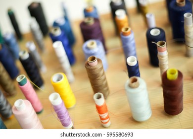 A high angle view of a large group of displayed bobbins of thread on a wooden board.