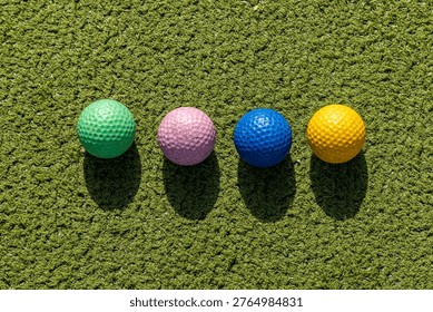 A high angle view of a line of multi-coloured golf balls on a crazy golf course