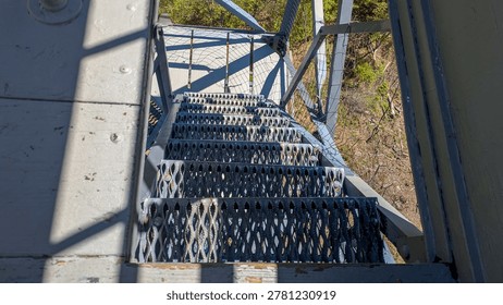 High angle view looking down steep metal grating stairs of observation tower