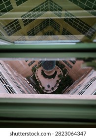 High angle view looking down through a window pane at an inner building courtyard with garden landscaping and a central structure.
