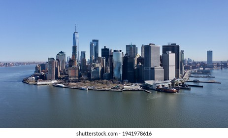 A high angle view of lower Manhattan, NY on a sunny day with no clouds. The East River is calm and there are no boats in the water.