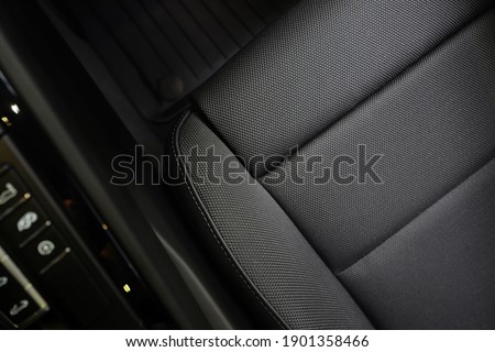 High angle view of luxury sport car front passenger seat and detail high end fabric and stitch texture along with blurred gear shift control buttons. Design element and car interior background.