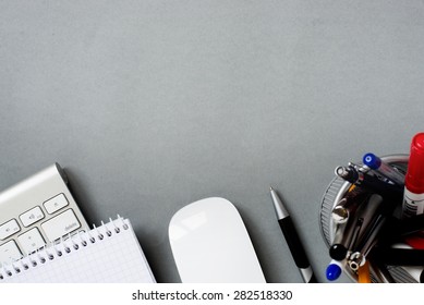 High Angle View Of Mac Computer Keyboard And Mouse With Note Pad And Full Pen Holder On Grey Desk With Ample Copy Space