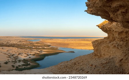High angle view of Magic Lake in the heart of Fayoum desert surrounded by sand dunes and rocky mountains in Egypt