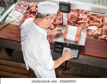 High angle view of male butcher weighing sausages at display cabinet in butchery - Powered by Shutterstock