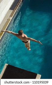 High Angle View Of A Male Diver Jumping From Springboard Into The Pool