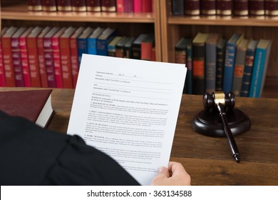 High angle view of male judge reading legal documents at desk in courtroom - Powered by Shutterstock